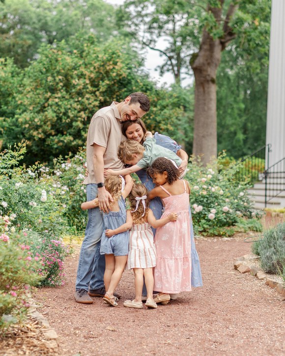 Lauren and her husband embraced by their four children in a garden